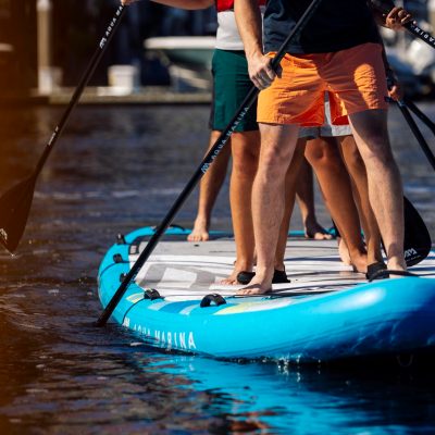 People paddleboarding on a large blue paddleboard in calm water.
