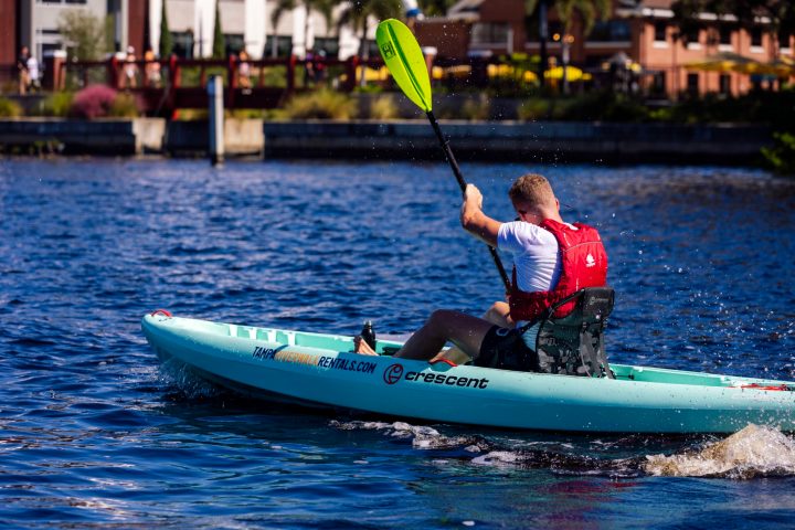 Man kayaking on a sunny day in a blue kayak on a lake.