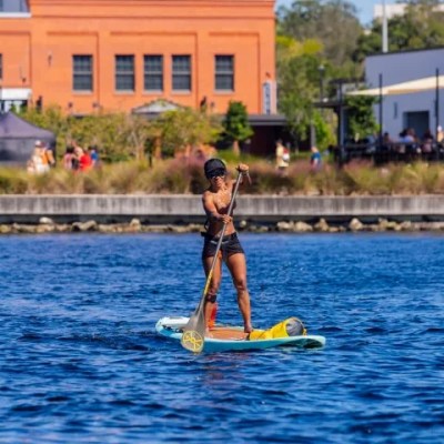 Person paddleboarding on a lake with buildings in the background.